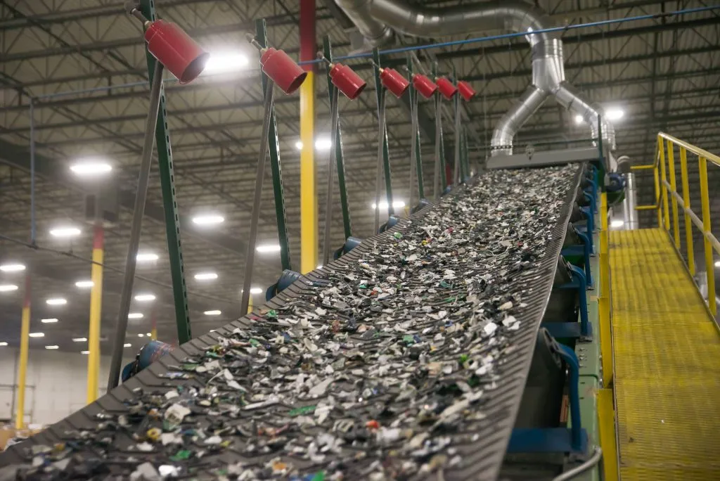 A conveyor carrying shredded material through a secure recycling facility.