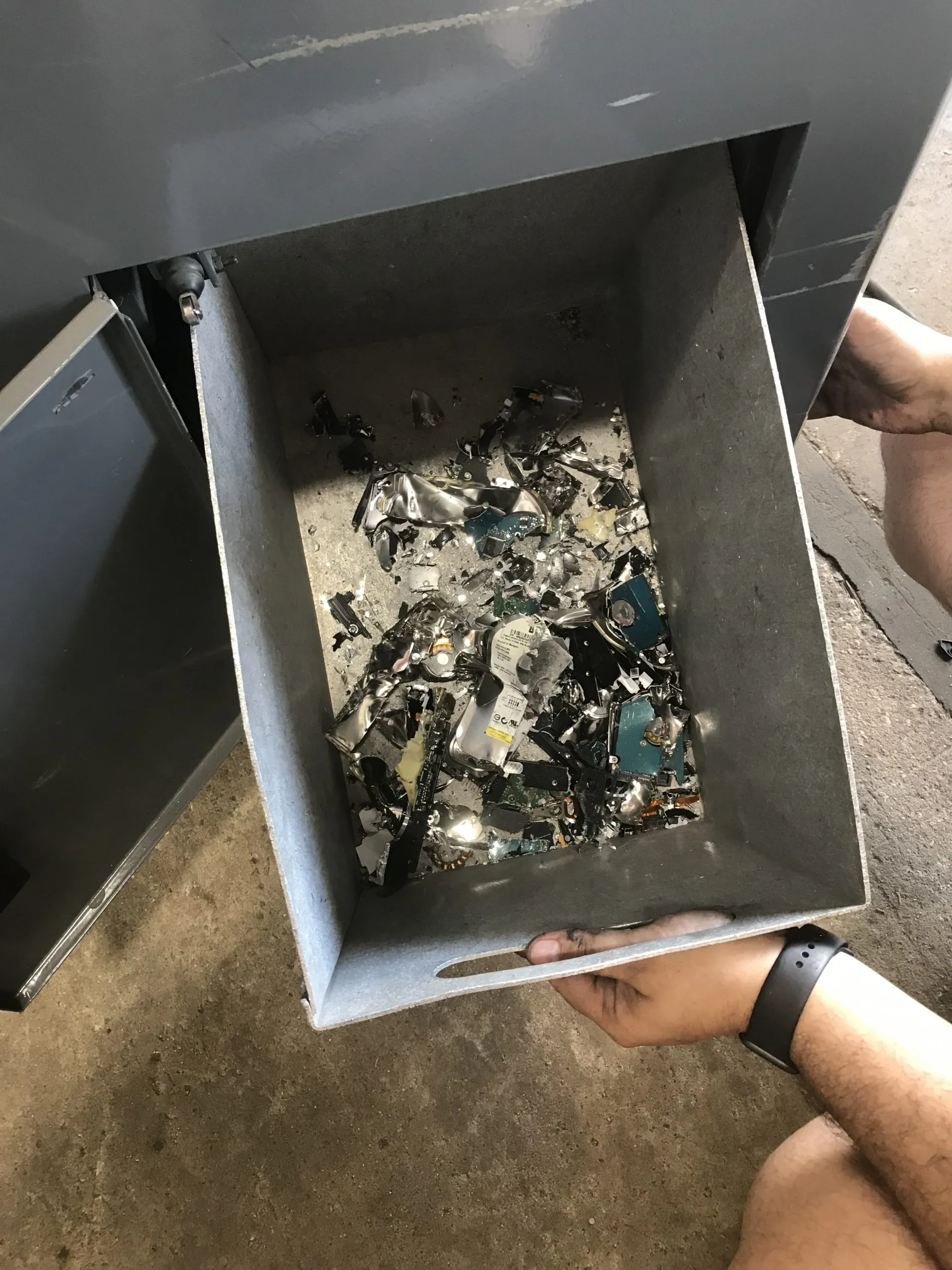 A man inspecting a metal box containing destroyed metal pieces.